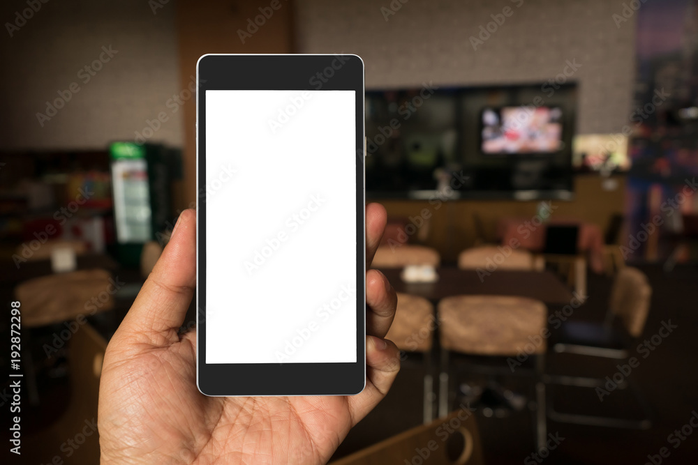Hand holding black mobile smart phone with blank black screen in coffee shop cafe. technology and lifestyle concept.