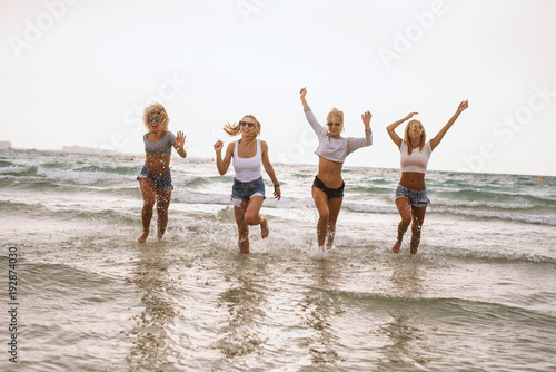 Four sexy ladies running in the sea water and having fun on the beach.
