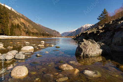 Midday Autumn landscape calm river in the Caucasus Mountains with rocks in the near term