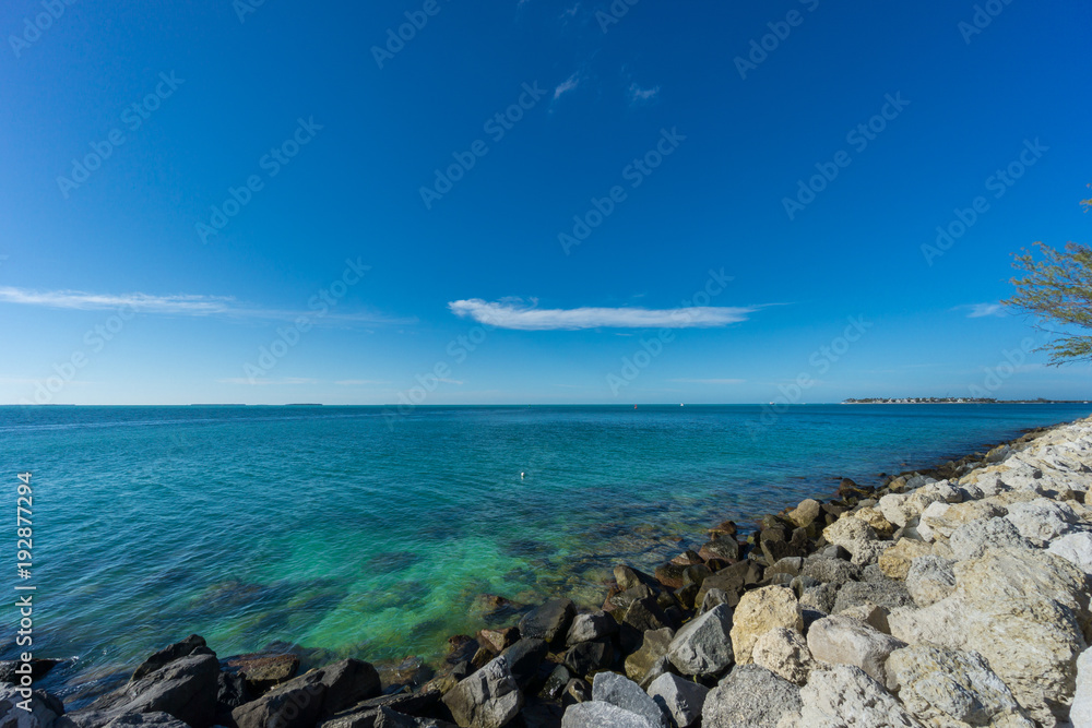 USA, Florida, Blue clean clear ocean water at key west behind white rocks