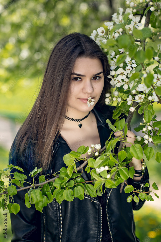 Glamorous young caucasian woman in black leather jacket in a flowery garden Glamorous young caucasian woman in black leather jacket in a flowery garden
