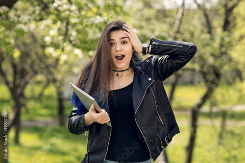 Young girl in the park with a tablet in hand.