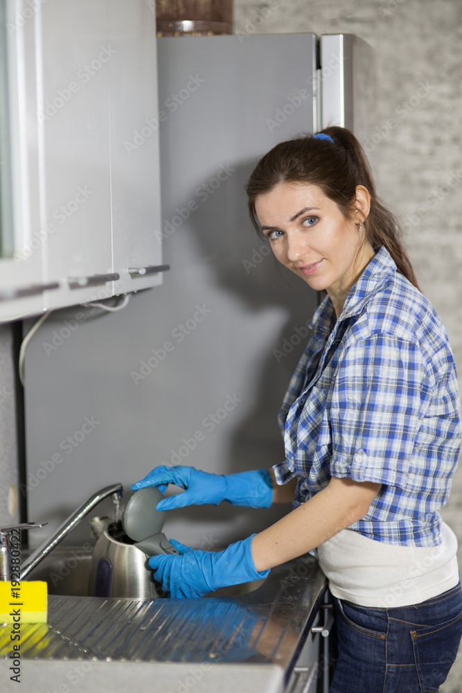 Young woman washing dishes in the kitchen