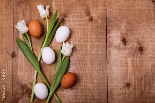 Tulips flowers and eggs decoration on wooden background. Top view, text space