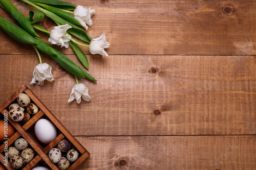 Tulips and eggs in wooden box on the table. Top view  text space