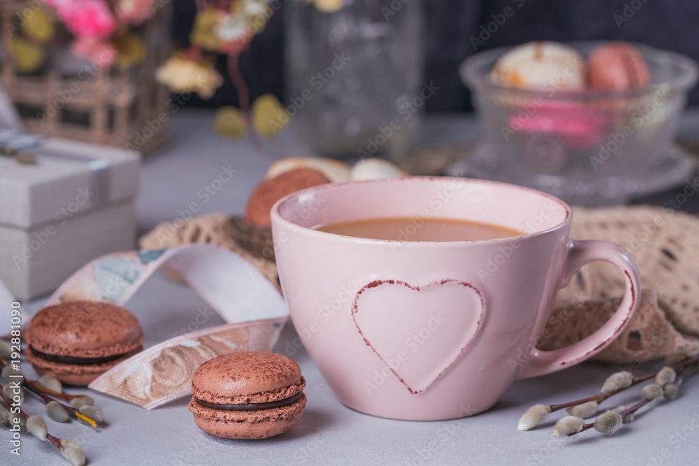 Fototapeta premium Pink coffee mug with sweet pastel french macaroons, gift box and pussy willow