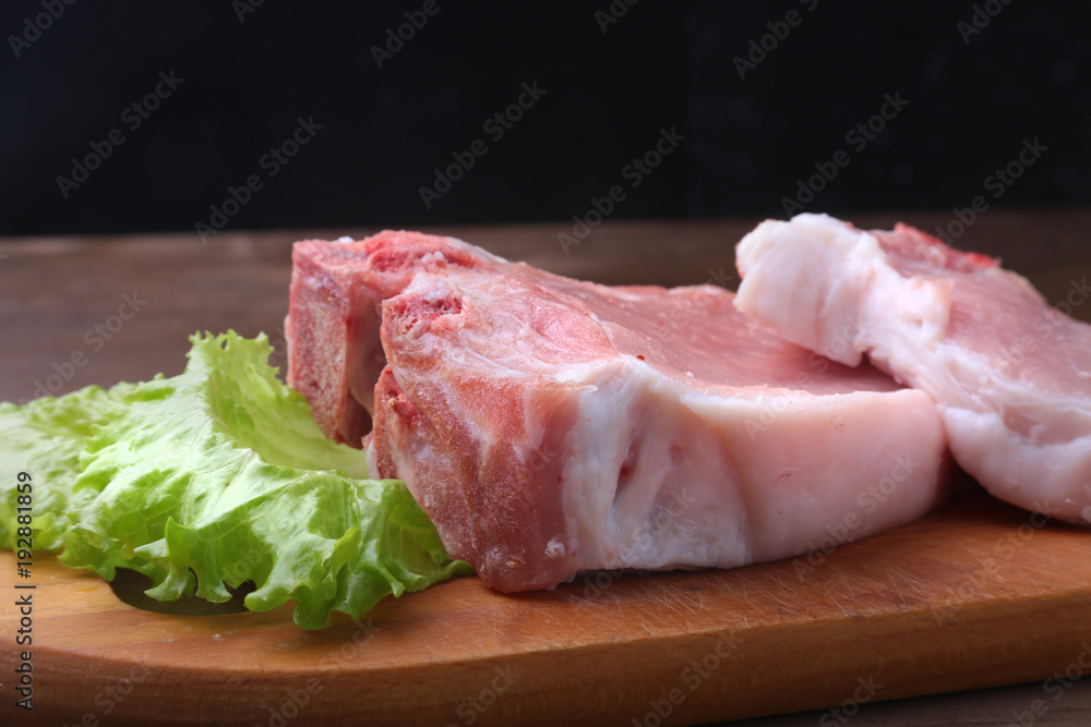 Raw steak on a rustic cutting board with salt, pepper and grinder for spices . Black Background for copy space. Top View. Raw steak on a rustic cutting board with salt, pepper and grinder for spices . Black Background for copy space. Top View.