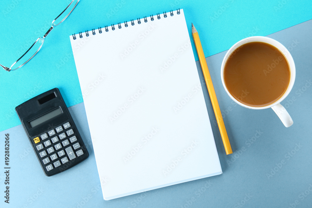 Top view image of open notebook with blank pages and coffee on blue background, ready for adding or mock up. Still life, business, office supplies or education concept. Top view image of open notebook with blank pages and coffee on blue background, ready for adding or mock up. Still life, business, office supplies or education concept.