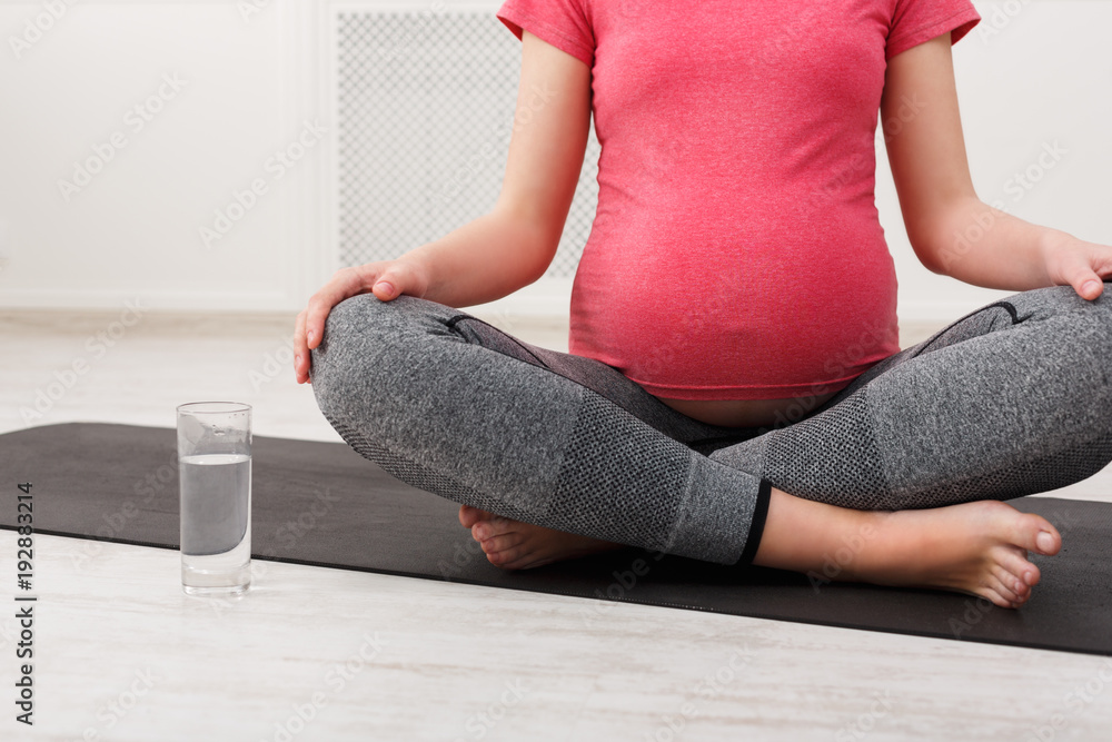 Unrecognizable pregnant woman with glass of water