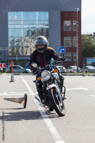 L-driver motorcyclist doing exercise with cones on asphalt ground photo