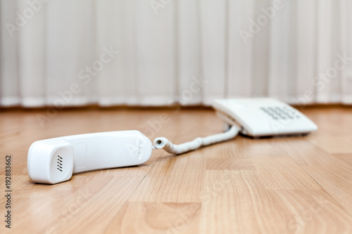 Landline white phone is on floor with dropped handset