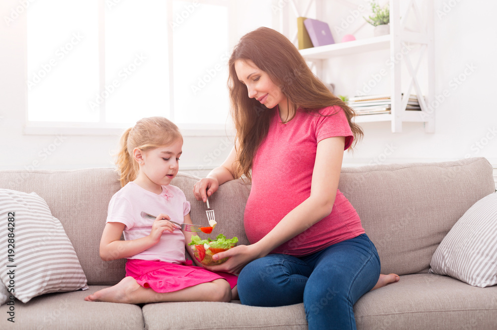 Little girl and her mom eating salad at home