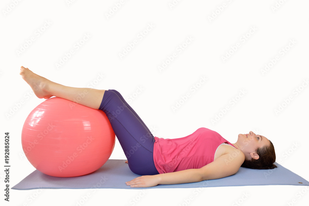 Fototapeta premium Shot of an attractive young woman working out with an exercise ball against a white background