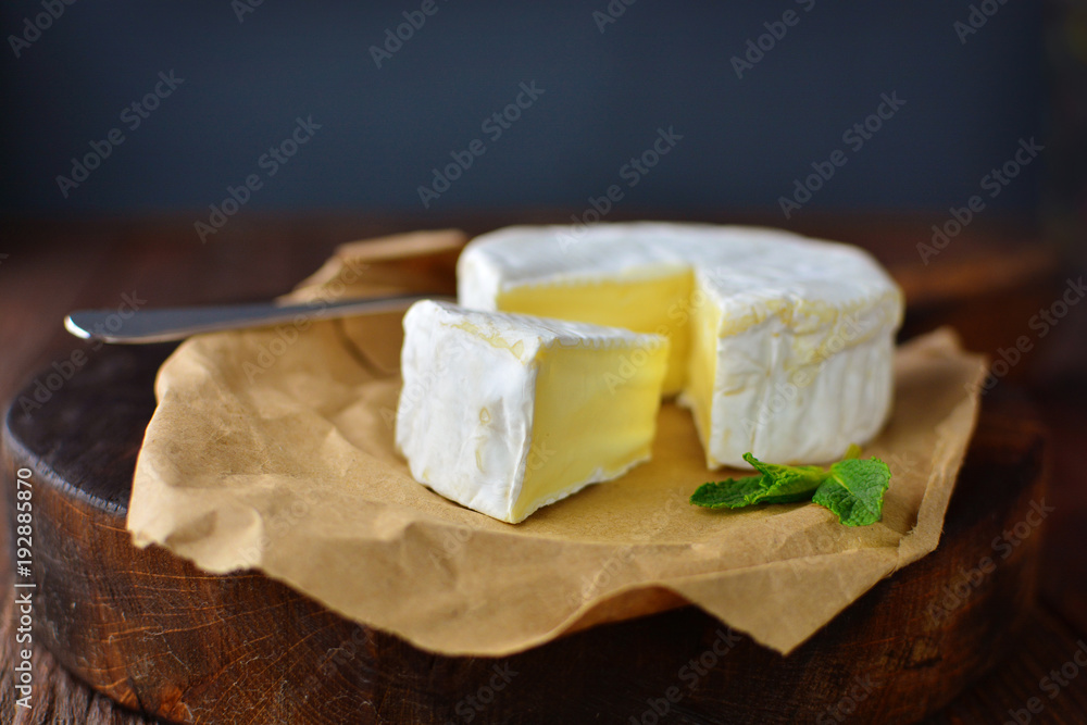 Tasty camembert cheese cut on an old oak cooker in a home rustic kitchen.