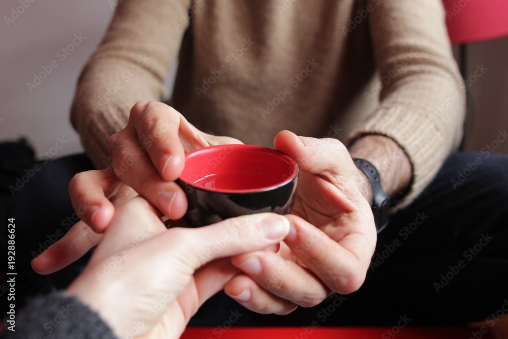 Obraz premium Hands around cup of tea shared by couple