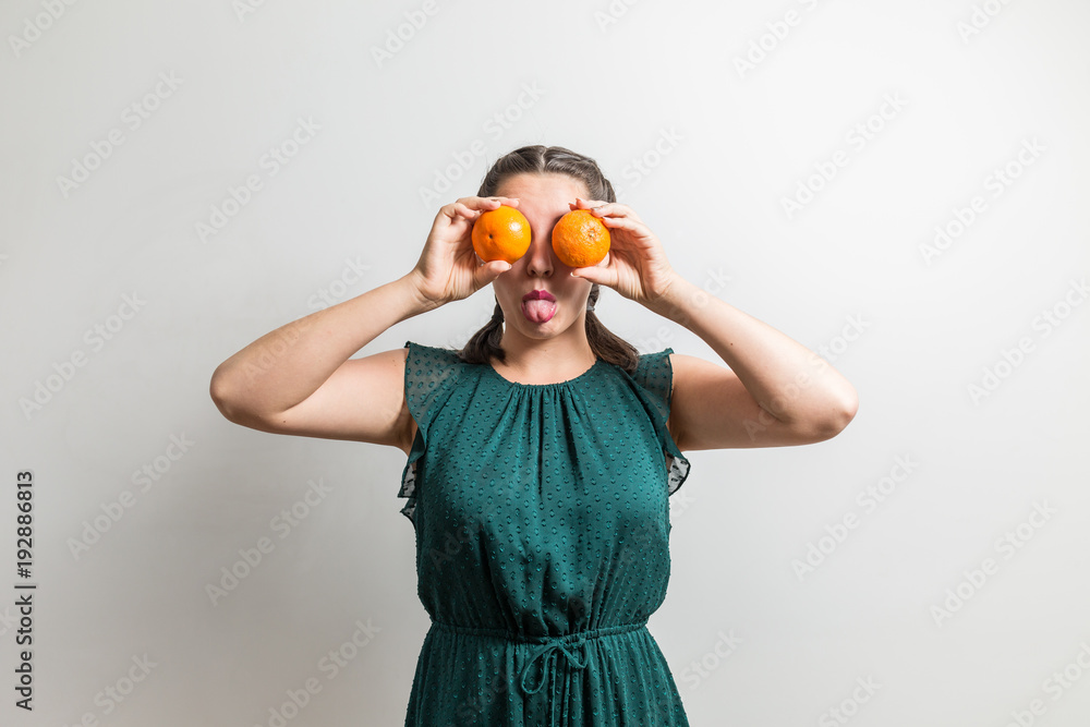 Cute girl shows tongue while holding oranges like eyes Cute girl shows tongue while holding oranges like eyes