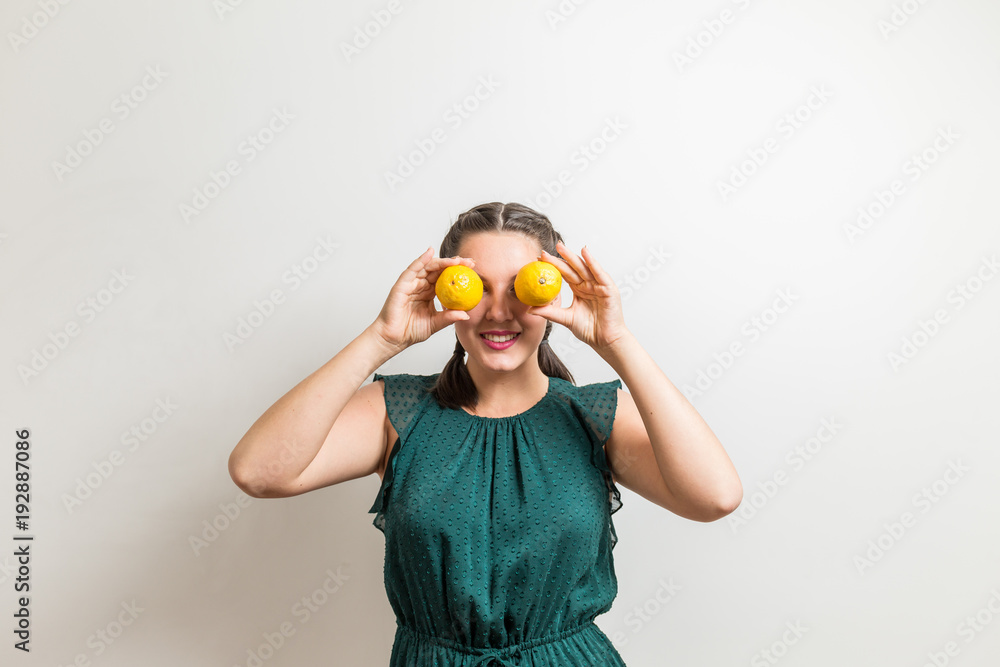 Attractive woman holds limons in front of her eyes and smiles Attractive woman holds limons in front of her eyes and smiles