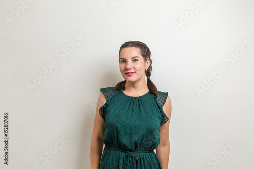 Beautiful girl stands next white wall in green dress