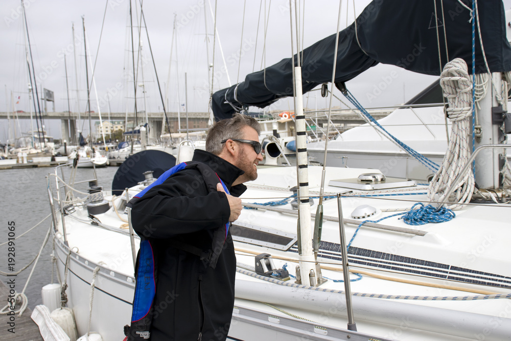 Fototapeta premium Charleston Marina South Carolina, February 17, 2018 - man putting on lifejacket next to sailboat at charleston marina