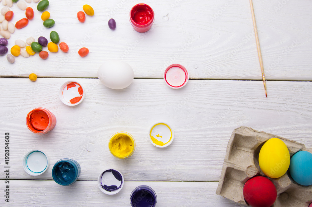 Easter eggs, paint and candy on wooden table