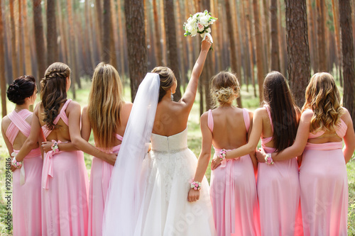 Bride and bridesmaids in pink dresses having fun at wedding day. Happy marriage and wedding party concept