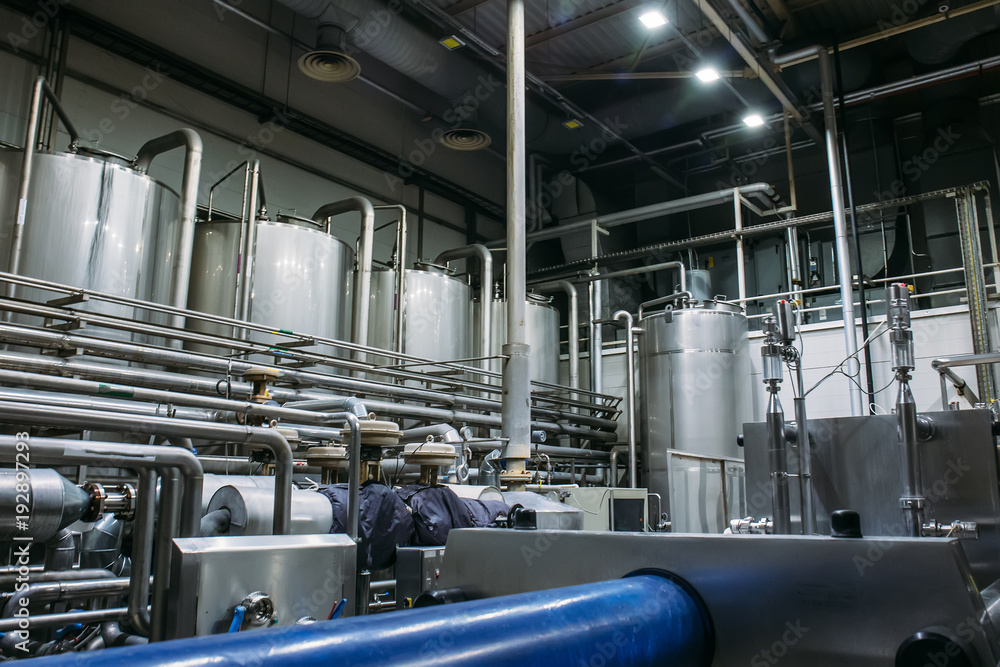 Stainless steel brewing equipment : large reservoirs or tanks and pipes in modern beer factory. Brewery production, industrial background Stainless steel brewing equipment : large reservoirs or tanks and pipes in modern beer factory. Brewery production, industrial background