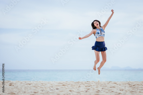 Happy Asian woman jumping on the beach