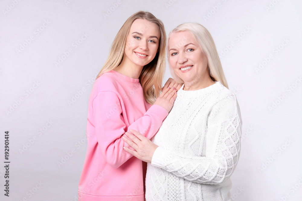 Young daughter and mother on light background Young daughter and mother on light background