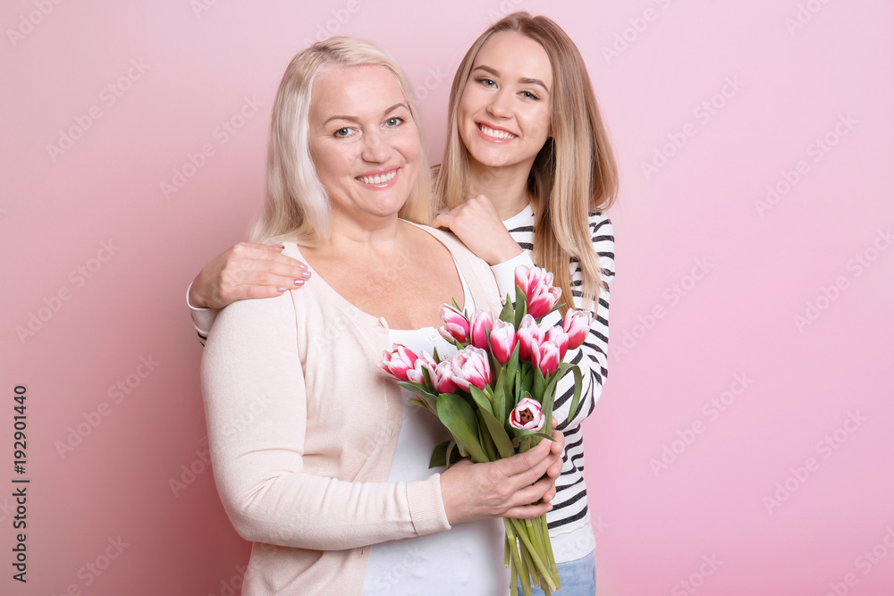Young daughter and mother with bouquet of flowers on color background Young daughter and mother with bouquet of flowers on color background