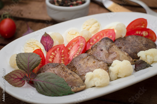 Fried chicken liver with vegetables and herbs. Wooden background. Top view