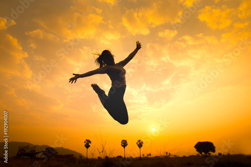 Silhouette of happy woman jumping over sunrise. Concept image for symbolic of successful, image made warmth tone.