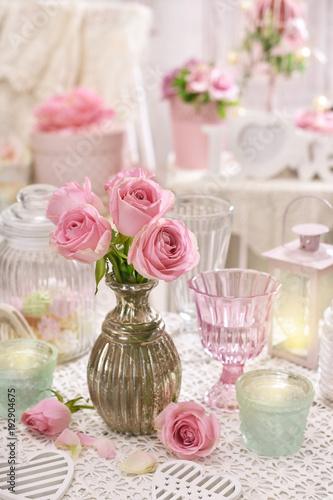 pink roses in vase on the table in shabby chic style interior