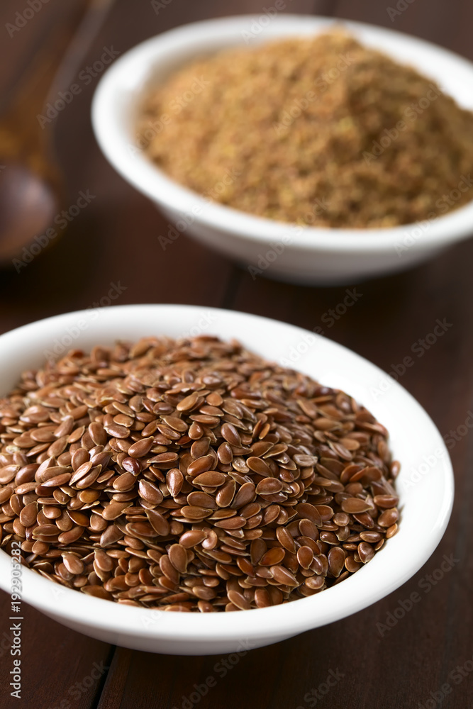 Whole brown flax seeds or linseeds and ground linseeds in small bowl, photographed on dark wood with natural light (Selective Focus, Focus one third into the image) Whole brown flax seeds or linseeds and ground linseeds in small bowl, photographed on dark wood with natural light (Selective Focus, Focus one third into the image)