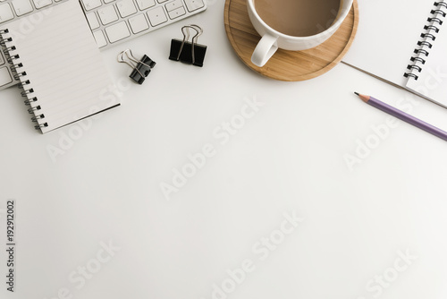 White office desk table with blank notebook, computer, supplies and coffee cup. Top view with copy space. Flat lay.