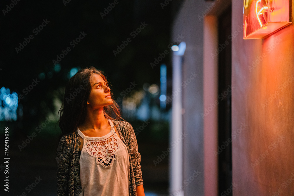 A portrait of an attractive Indian Lady standing in the hallway as she was amazed at what she saw on the wall. She wears a very comfortable casual wear, and during the night she enjoys wandering alone