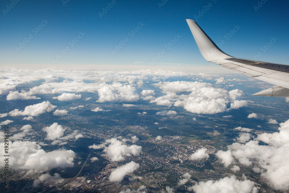 beautiful view from window porthole. wing of the plane on a background of clouds and blue sky. flight of airplane over city. beautiful view from window porthole. wing of the plane on a background of clouds and blue sky. flight of airplane over city.