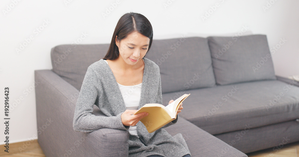 Woman reading book and sitting on sofa