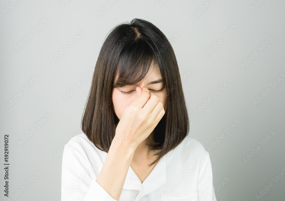 The woman is touching face between the eyebrows, to show her headache. Causes may be caused by stress or migraine. Or because too much work. The woman is touching face between the eyebrows, to show her headache. Causes may be caused by stress or migraine. Or because too much work.