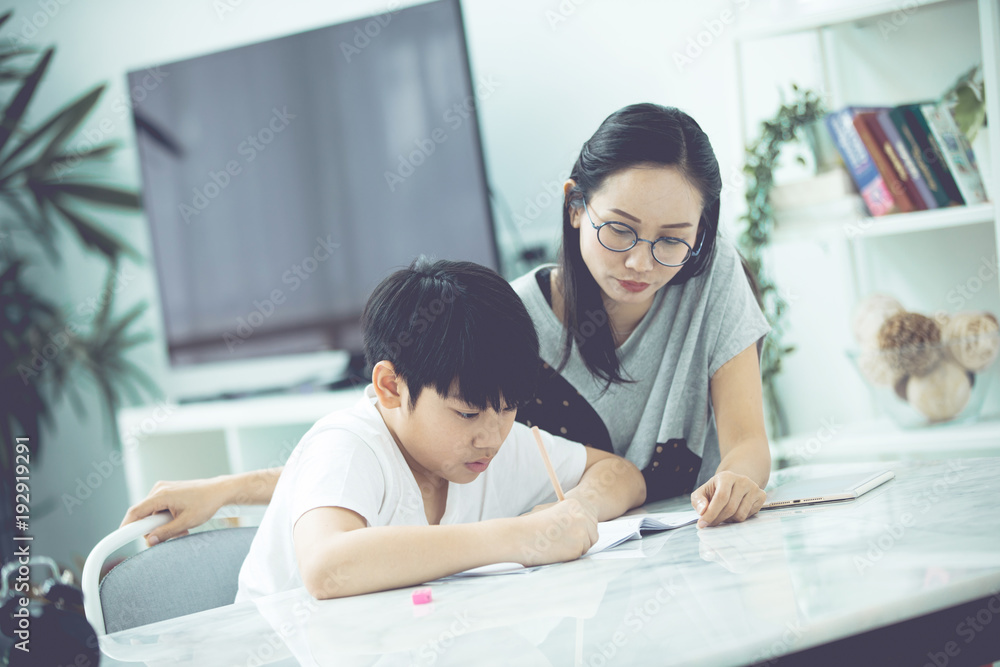 Asian boy with mother teaching and learning your homework at home Asian boy with mother teaching and learning your homework at home