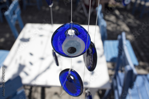 Hung, decorative evil eyes with blue, wooden chairs and white table in Cunda (Alibey) island.