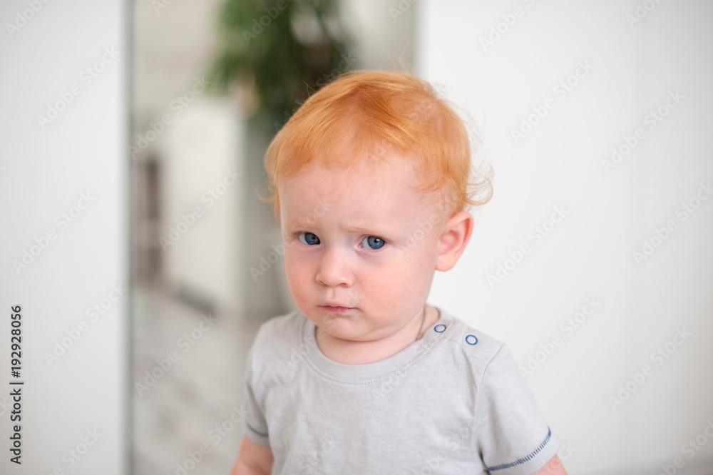 The curly-haired redhead boy looks wary