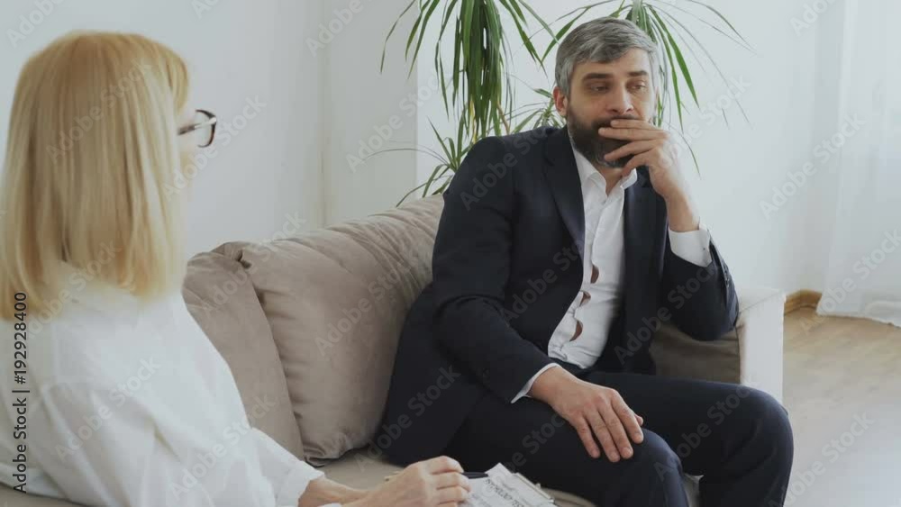 Upset businessman talking about his porblems with female psychologist Upset businessman talking about his porblems with female psychologist