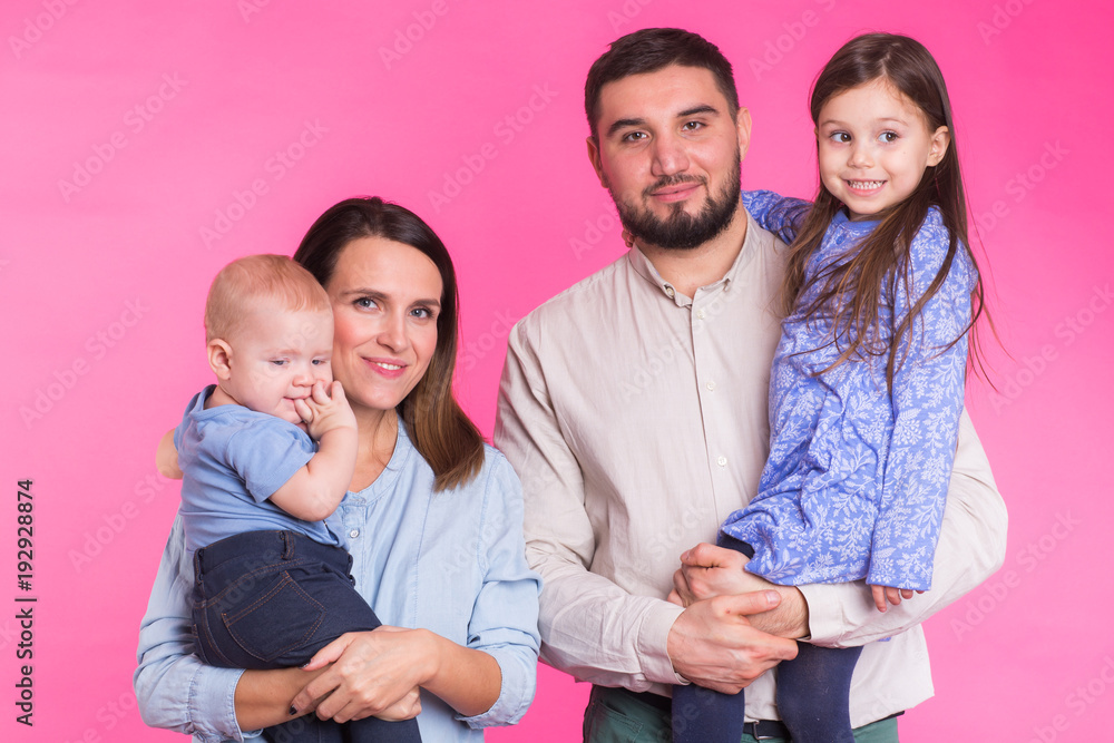 Cute family posing and smiling at camera together on pink background