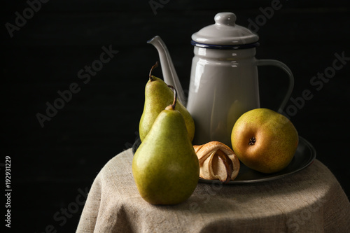 Still life with pears on table against dark background