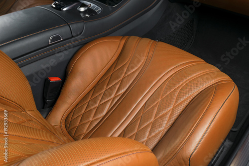 Modern Luxury car inside. Interior of prestige modern car. Comfortable leather brown seats. Orange perforated leather cockpit. Automatic transmission. Modern car interior details © Aleksei