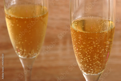 Two glasses with champagne. Bubbles in the glasses create a holiday atmosphere. Light wooden background. Close-up. Macro photography.