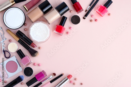 Makeup brush and decorative cosmetics on pink background with empty space. Top view