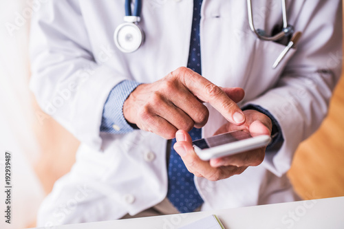 Senior doctor with smartphone working at the office. photo