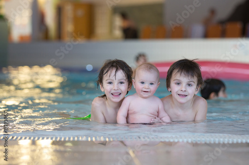 Three little children,  cute baby boy and two older brothers, swimming happily in a shallow pool © Tomsickova