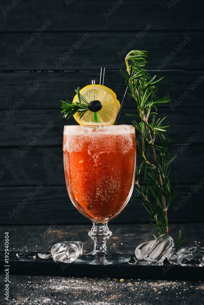 Fototapeta premium Alcoholic Cocktail Bloody Mary. Tomato juice and rosemary. On a black wooden background.